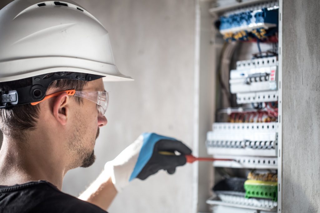 man-electrical-technician-working-switchboard-with-fuses-installation-connection-electrical-equipment